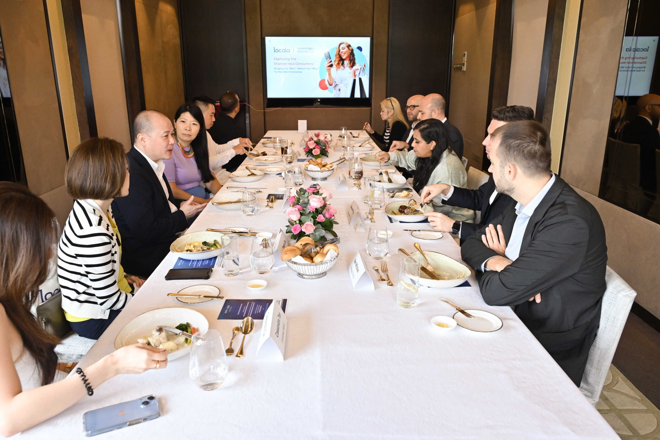 Photo of the marketing interactive team and locala around a table. Vincent pang, MD APAc is desmonstrating omniplanner on a screen